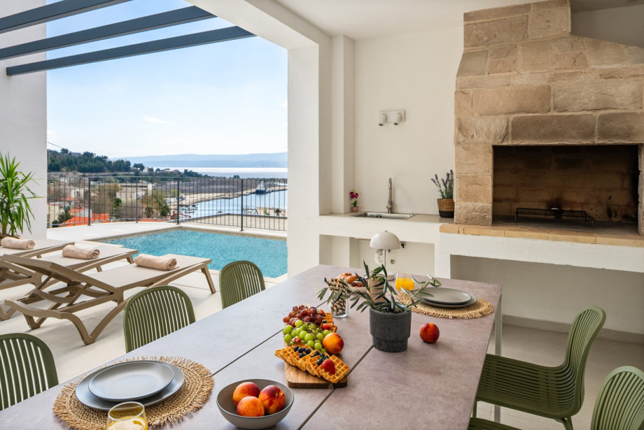 The covered outdoor dining area features a barbecue for enjoying al fresco meals with sea views.