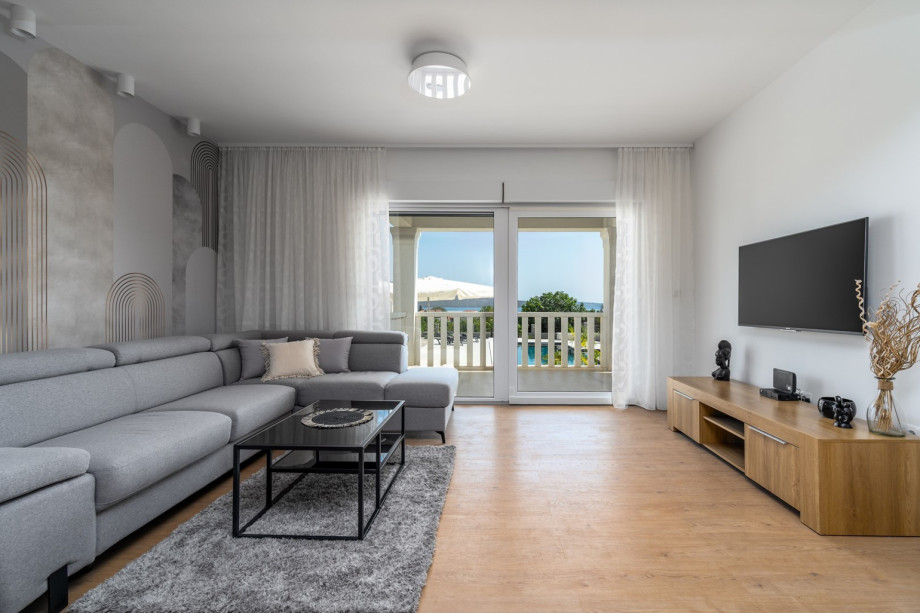 Living room on the ground floor with a comfortable sofa and glass doors toward the pool area