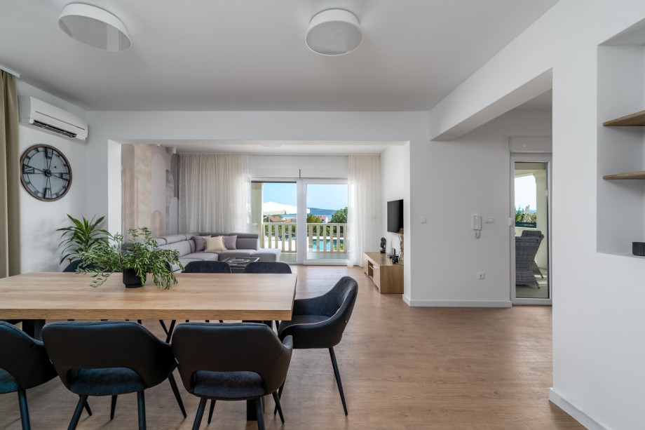 The ground floor offer dining table, a living room with a comfortable sofa and glass doors toward the pool area