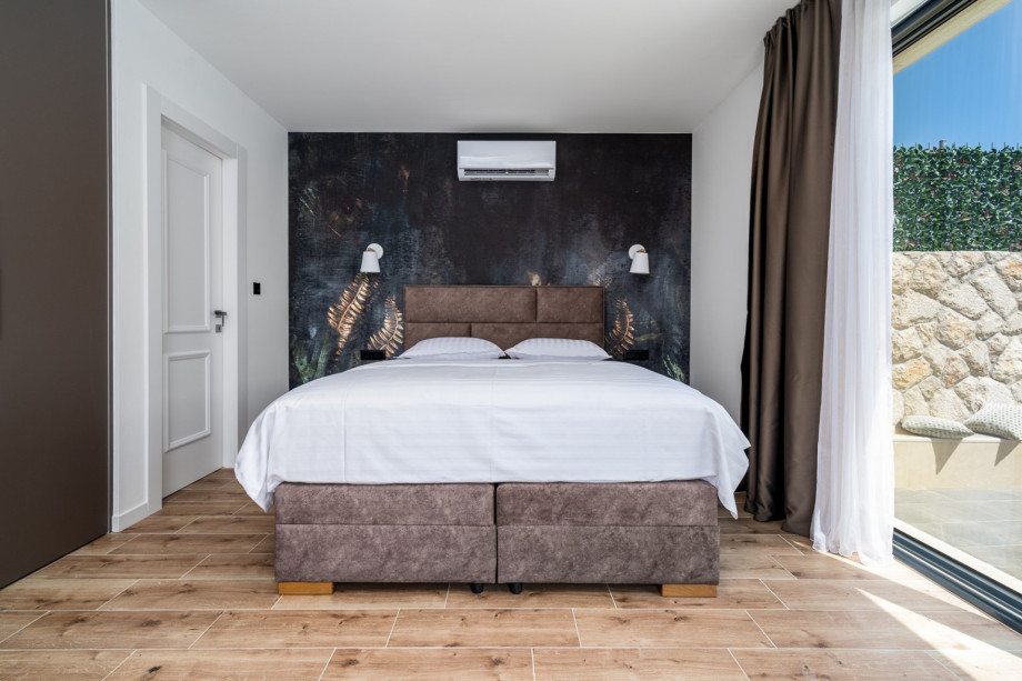 The bedroom has two glass walls toward the pool and sun deck area.