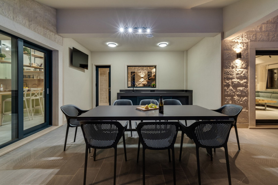 Outdoor dining area with summer kitchen and a TV, and a traditional barbecue