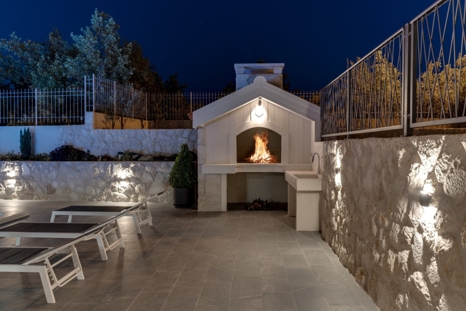 Outdoor dining area with summer kitchen and a TV, and a traditional barbecue