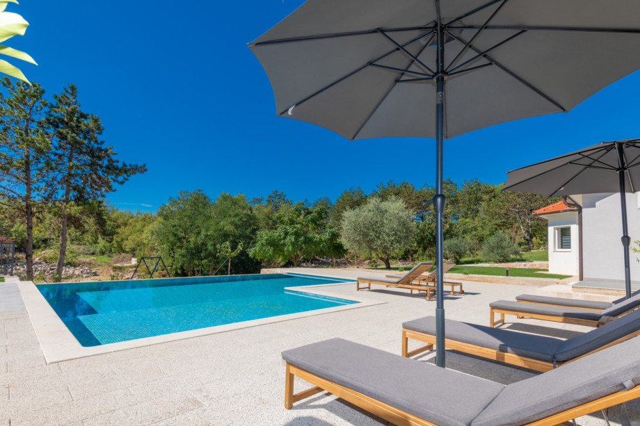 The sun deck area is furnished with comfortable loungers and umbrellas surrounding the infinity pool.