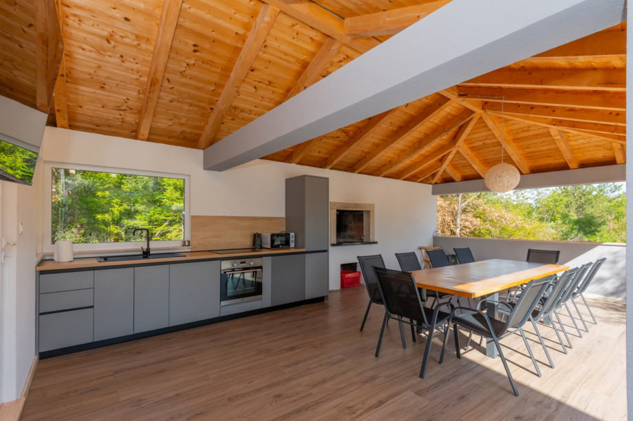 The 50 sqm summer kitchen is fully equipped with an electric hub, oven, and a dining table for 10 people.