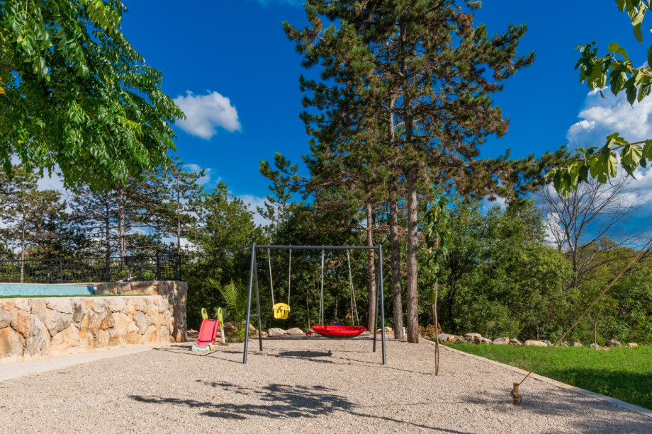 Grassy plot features a swing and slide for children to enjoy.