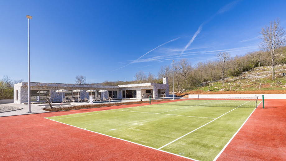 Ein Tennisplatz im Freien mit Tennisausrüstung und Beleuchtung für abendliches Spielen
