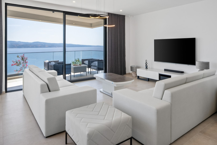 The living space is designed with large glass doors that flood the space with natural light and connect you to the pool and sea views