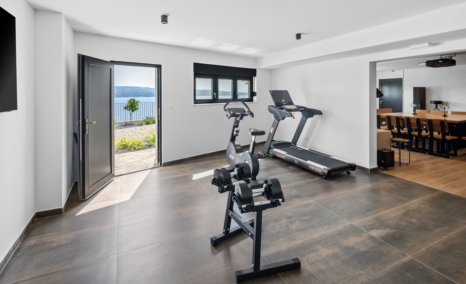 A gym area featuring a professional treadmill, exercise bike, multifunctional exercise machine, weights, Pilates ball, and yoga mat