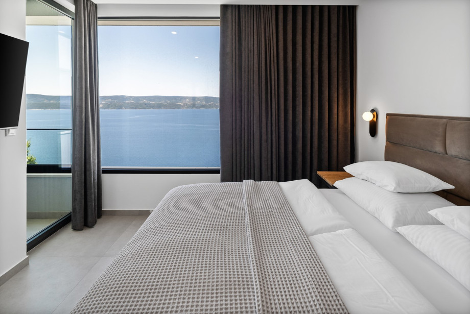 Bedroom No. 2 with a  king-size bed, TV, air conditioning, an en-suite bathroom with a shower, and a balcony offering fantastic sea vistas