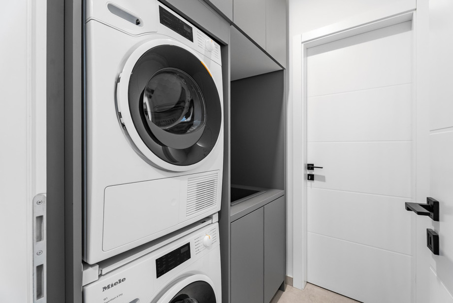 A  laundry room with a washer, dryer, iron, and ironing board