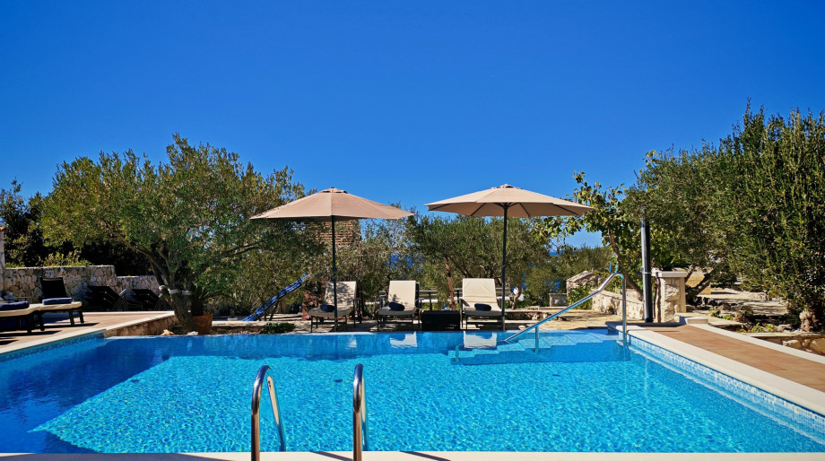 The large, no-chlorine private swimming pool is surrounded by olive trees and sun loungers.