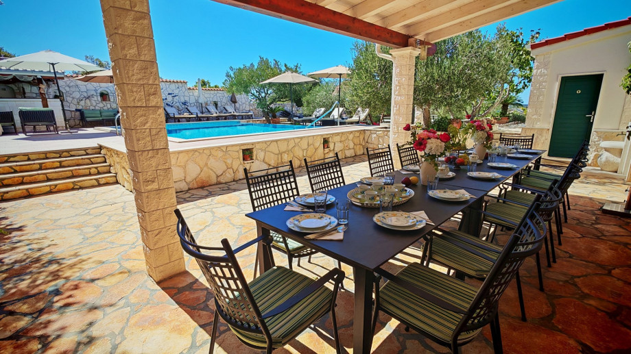 The covered outdoor dining area accommodates up to 14 guests for al fresco meals, perfectly set next to the pool level.