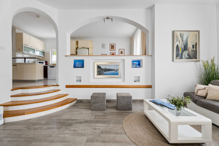 The bright, air-conditioned living area of the First Apartment features comfortable seating and a TV.