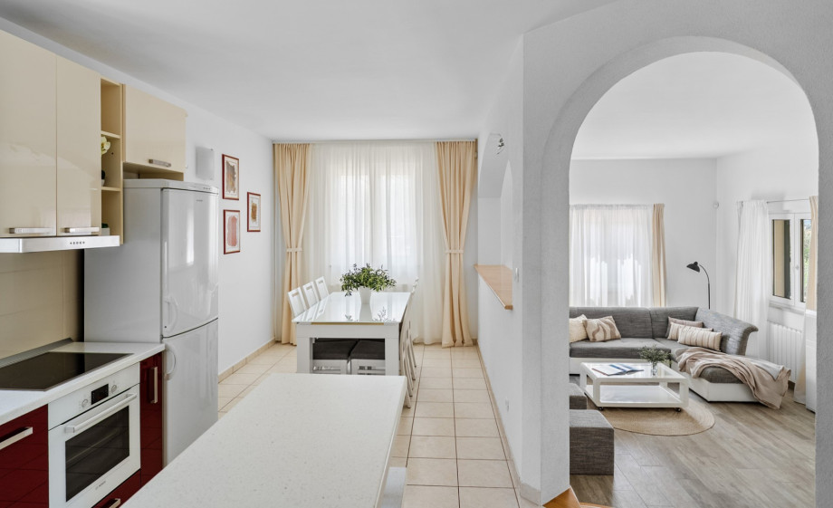 Kitchen view showing the open-plan dining and living area via steps and archway.
