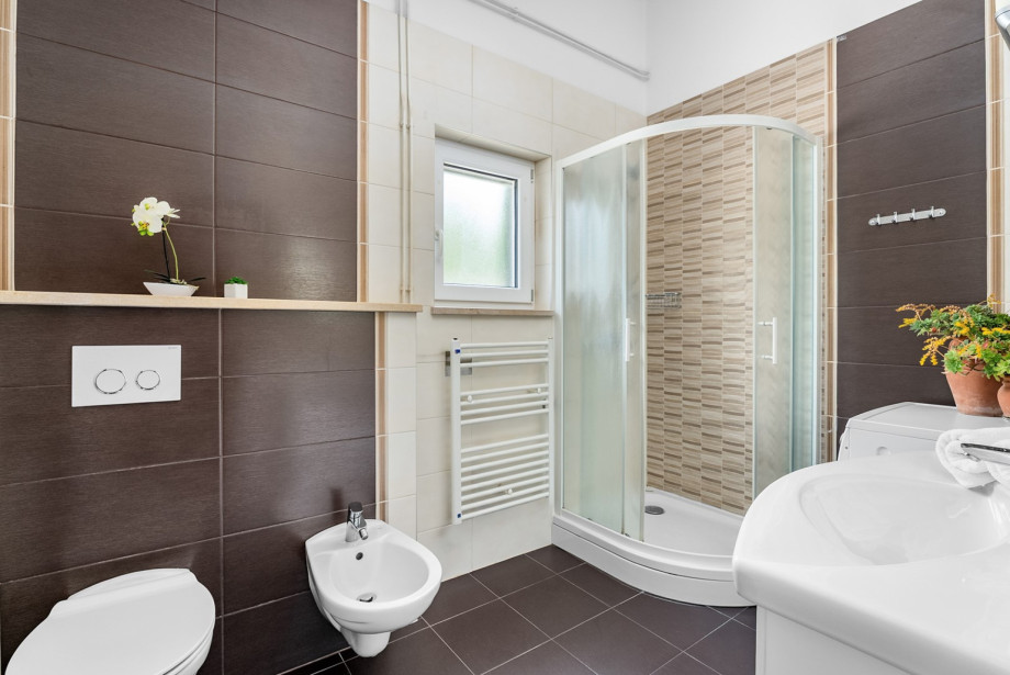 A well-maintained bathroom features a corner shower, a sink, and a convenient washing machine.