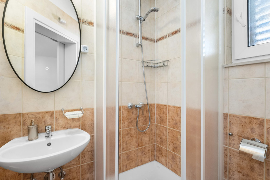 A family bathroom in one of the apartments features a tiled interior with a shower and basic amenities.