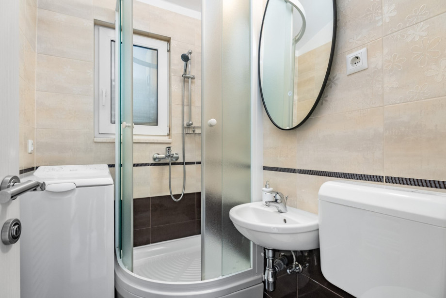 A compact family bathroom with a shower for the third apartment unit.