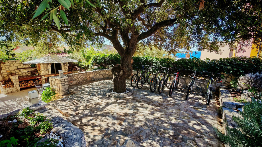 Seven complimentary bikes are provided and stored on a shaded stone patio near the barbecue, encouraging guests to explore the local area.