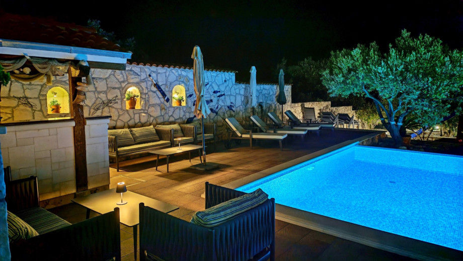 The pool area, lounge corner, and sun deck are beautifully illuminated at night, creating a perfect atmosphere for a starlit evening swim and relaxation.