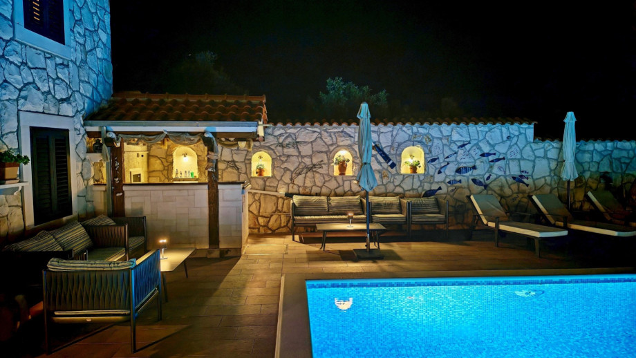 The poolside bar and lounge area are highlighted at night, offering a well-stocked and stylish spot for enjoying evening cocktails.