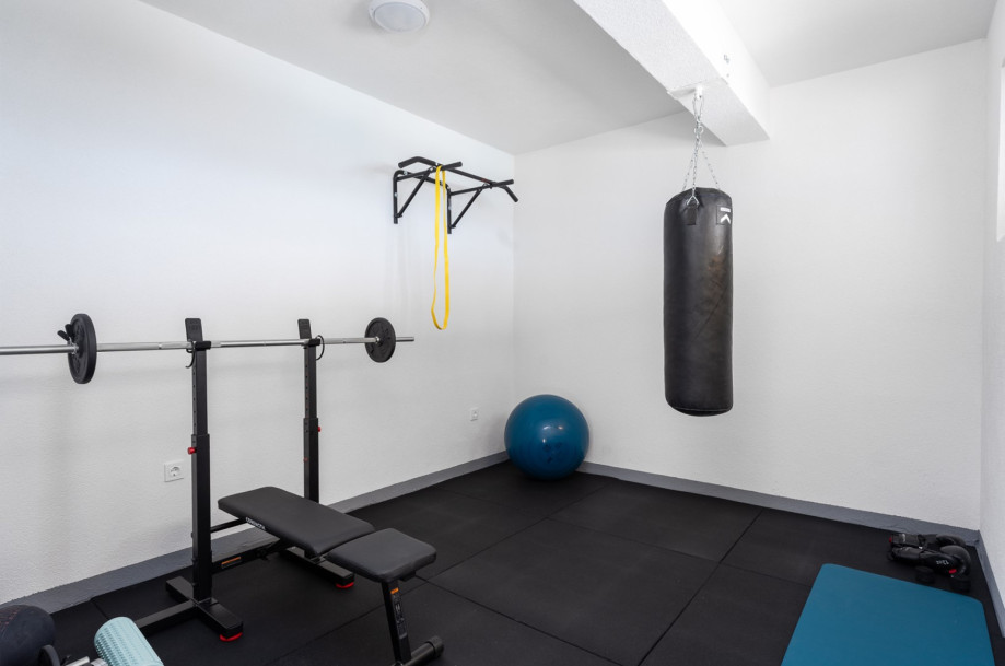 Gym with gym bench, boxing bag, and weights