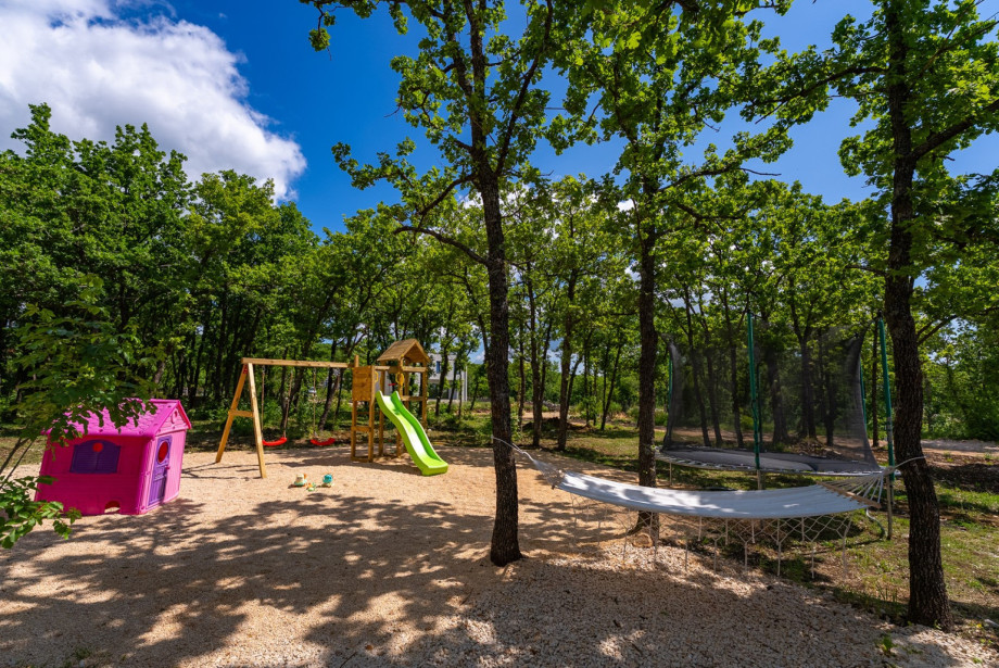 Kinderspielplatz mit Rutsche, Schaukel und Trampolin.