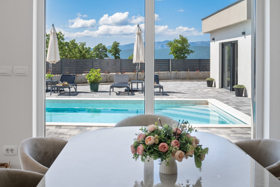 Vollständig klimatisiertes Wohnzimmer mit Essbereich für 8 Personen und Schiebetüren zum Pool.