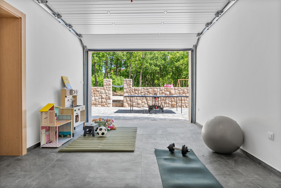 Der 20 m2 große Spielbereich umfasst eine Kinderecke mit Spielzeug sowie eine Fitnessecke mit Yogamatte, Gewichten und einem Pilatesball.