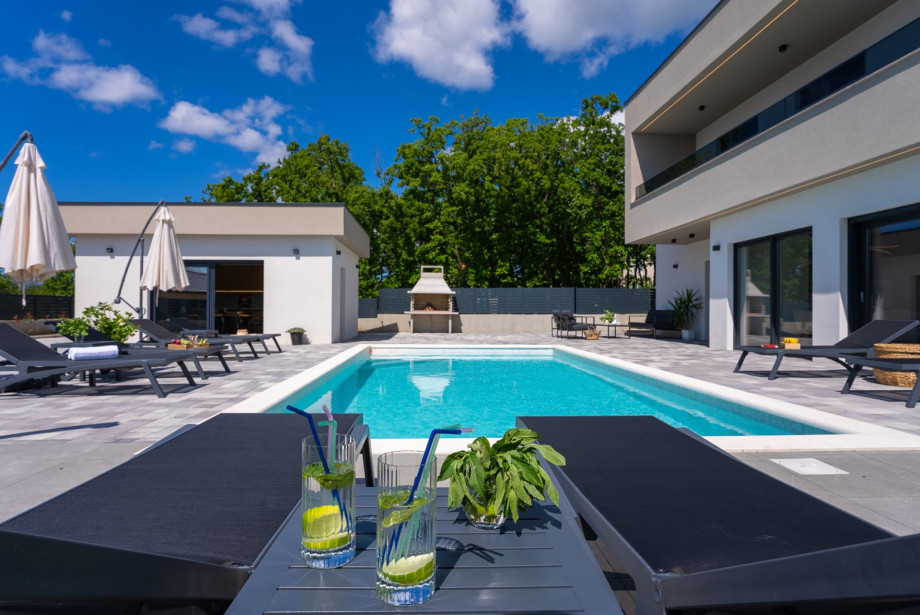 Neben dem Pool finden Sie eine voll ausgestattete Sommerküche und einen traditionellen Grill für das Leben im Freien.