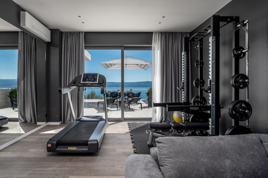 Fitnessstudio mit Laufband, Hantelbank mit mehreren Stationen und Gewichten.