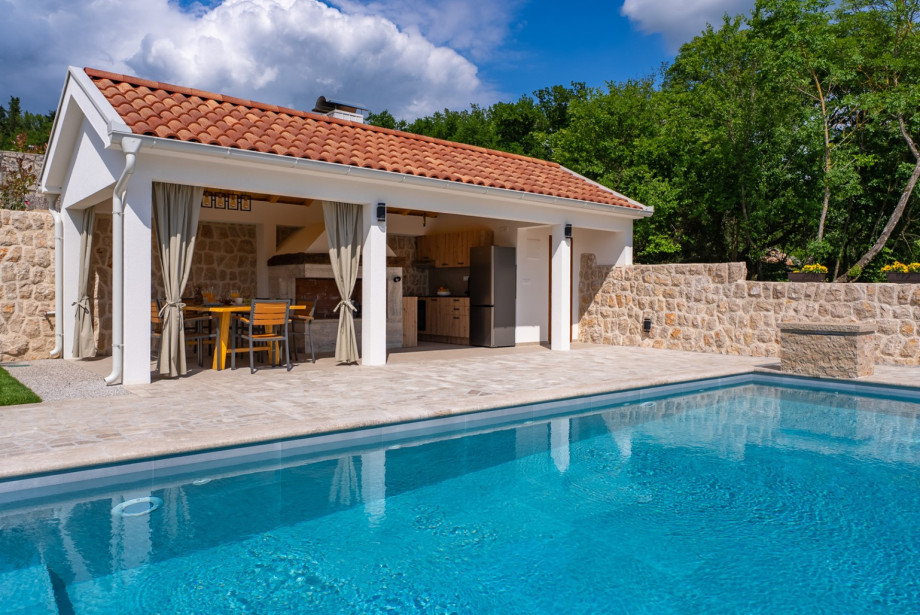 Beside the pool, find a fully equipped summer kitchen and a traditional barbecue for outdoor living.