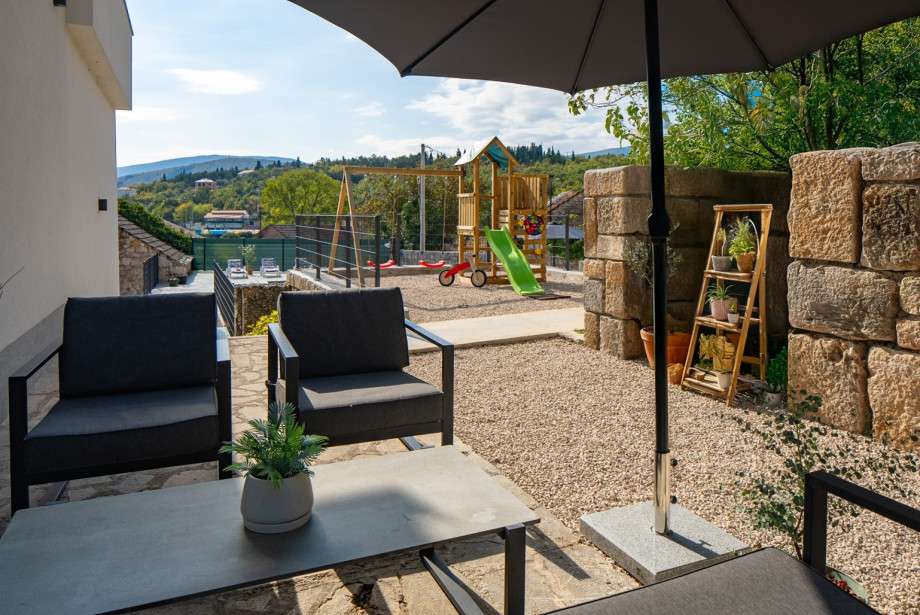 A cosy lounge corner is accessible from the kitchen, offering a shaded retreat near the kids' playground.