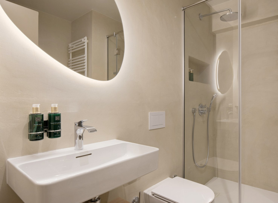 This contemporary bathroom features a clean, minimalist aesthetic with stone-textured walls and a rainfall shower.