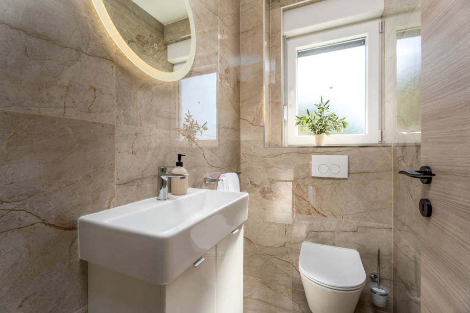 Separates WC und daneben eine Waschküche mit Waschmaschine, Trockner und Bügelzubehör.
