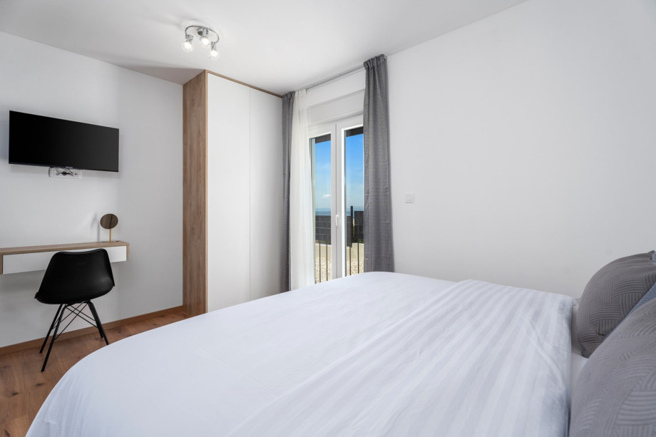 Schlafzimmer Nr. 1 mit Fernseher und Klimaanlage, mit Blick auf die umliegenden Olivenbäume.
