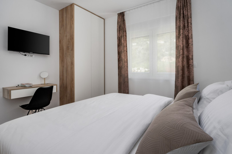 Schlafzimmer Nr. 4 mit eigenem Bad mit Dusche, Fernseher und Klimaanlage mit Blick auf die natürliche Umgebung und Olivenbäume.
