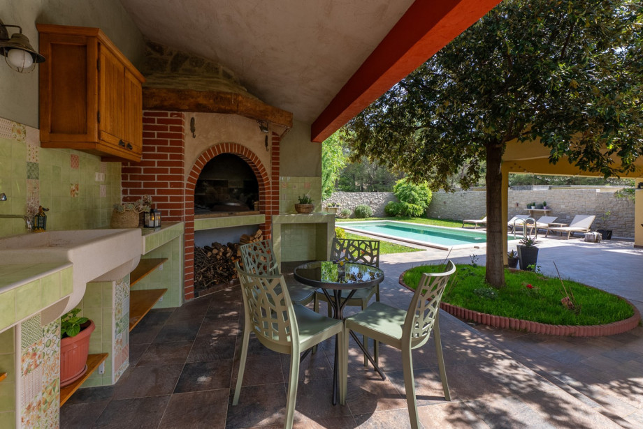 Shaded outdoor dining area with a barbecue for family gatherings.