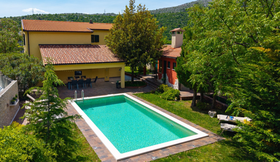 A private oasis with a heated pool, sun loungers, and lush garden views.