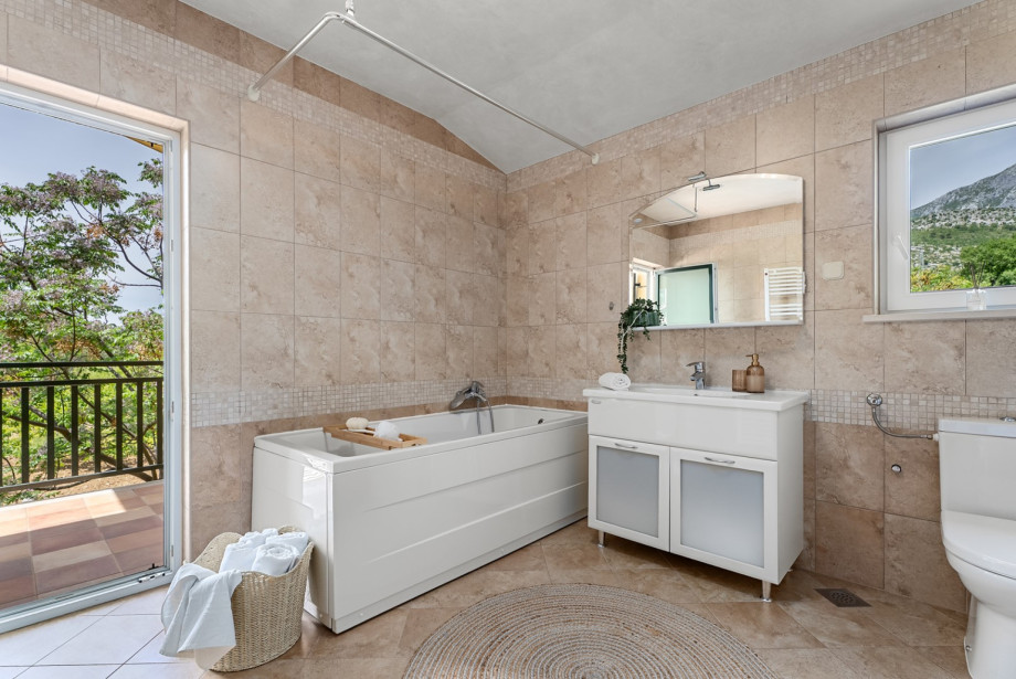 Family bathroom with a balcony, tub, and washing machine.