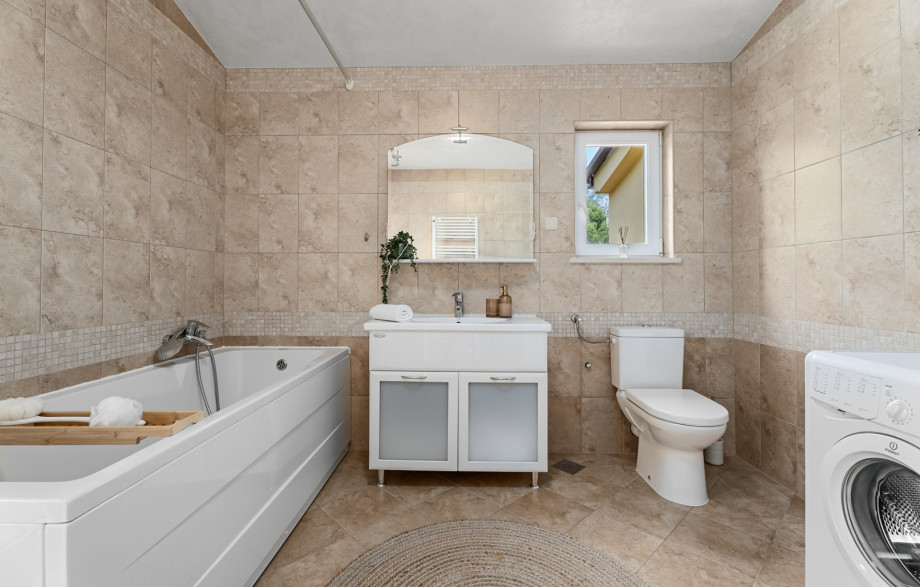 Spacious family bathroom with a bathtub and washing machine.