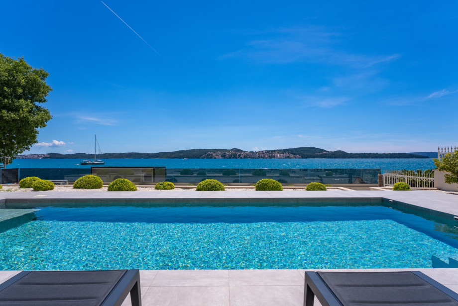 Luxury beachfront villa with breathtaking panoramic sea views under a clear blue sky.