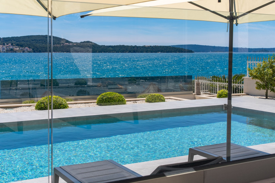 A luxurious seaside villa with a modern pool terrace, crystal-clear blue water, and a breathtaking panoramic view