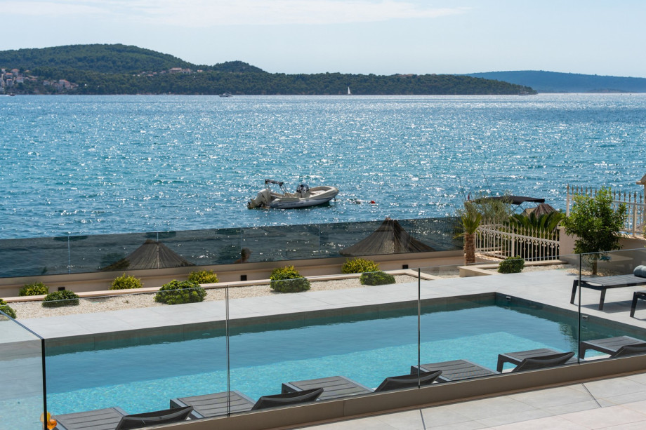 The endless blue of the sea and the tranquil pool blend into a scene of pure summer luxury.