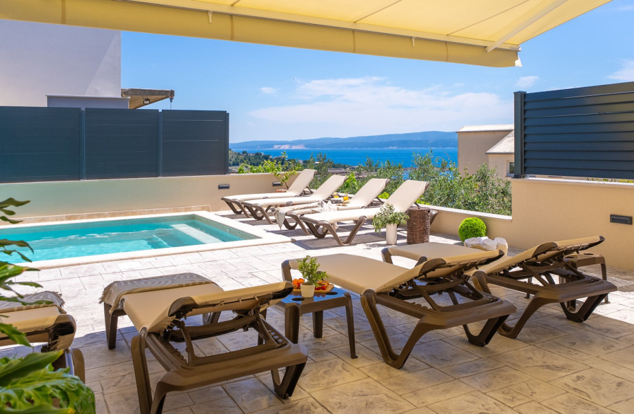 The outdoor area is ultimate relaxation and socializing, featuring ten deck chairs around the pool, a lounge area, and an outdoor shower