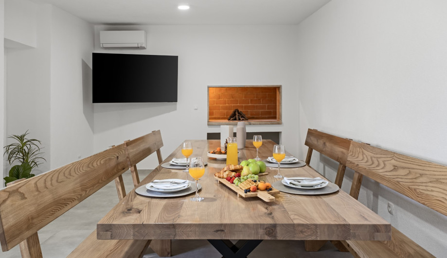 Summer kitchen with dining area for 14 people, including wood BBQ, A/C, and TV