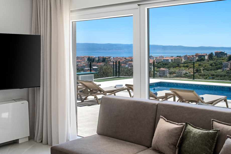 As you enter the ground floor, you’ll find an inviting living area that features a dining space for 10, a comfortable sofa, and a TV, all with breathtaking sea views
