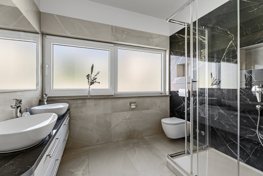 An en-suite bathroom with a shower, double sink, and a toilet