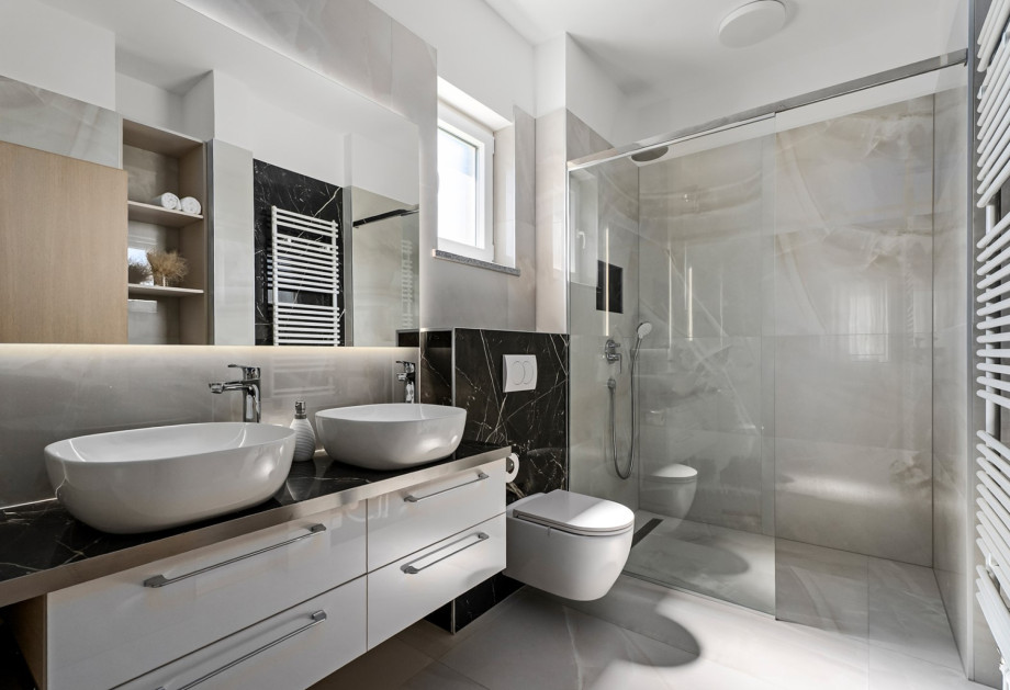 An en-suite bathroom with a shower, double sink, and a toilet