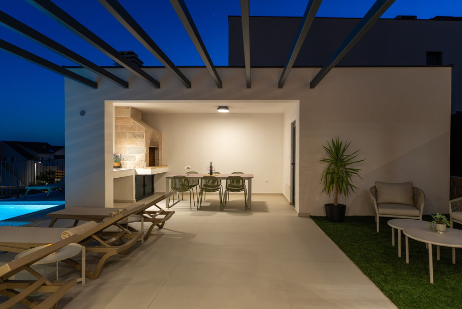 A covered outdoor dining area features a barbecue, perfect for al fresco meals.