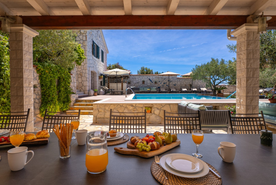 The 14-person dining table is sheltered and located next to the pool area.